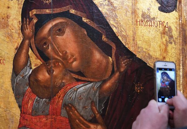 Посетитель фотографирует икону Богоматерь с младенцем на открытии выставки Шедевры Византии