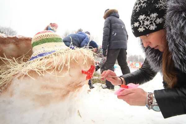Участница украшает снежную фигуру во время Арт-битвы Снеговиков в Московском Дворце пионеров на Воробьевых горах