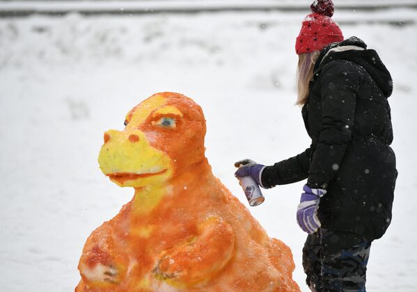 Участница наносит краску на фигуру из снега во время Арт-битвы Снеговиков в Московском Дворце пионеров на Воробьевых горах