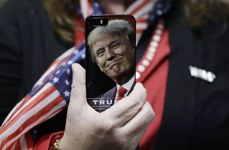 Женщина держит телефон с фотографией Дональда Трампа во время предвыборной кампании в США Женщина держит телефон с фотографией Дональда Трампа во время предвыборной кампании в США