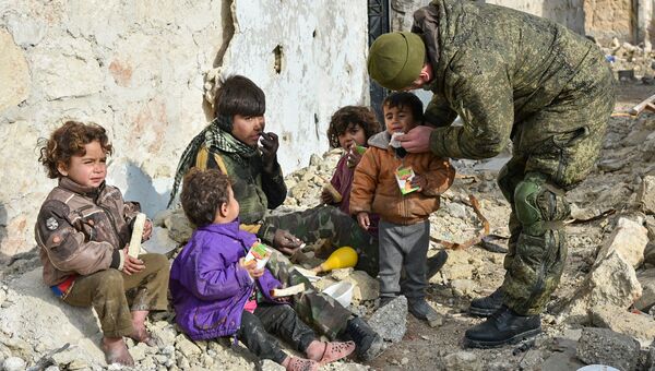 Военные инженеры сводного отряда Международного противоминного центра Вооруженных сил РФ, продолжающие работу по разминированию восточных районов сирийского города Алеппо, на одной из улиц Алеппо с сирийскими детьми. Архивное фото