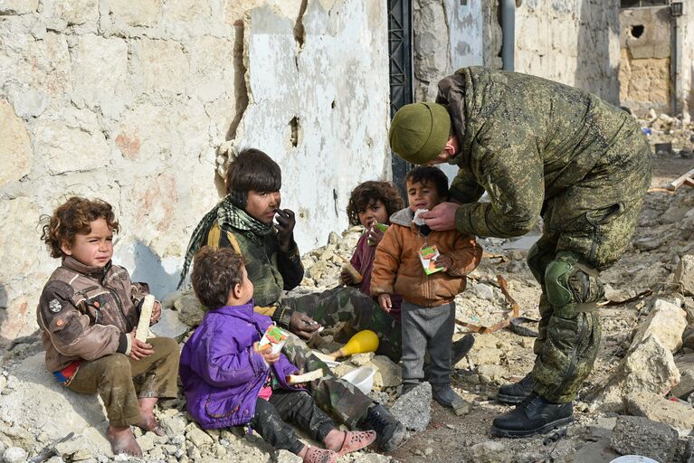 Военные инженеры сводного отряда Международного противоминного центра Вооруженных сил РФ, продолжающие работу по разминированию восточных районов сирийского города Алеппо, на одной из улиц Алеппо с сирийскими детьми