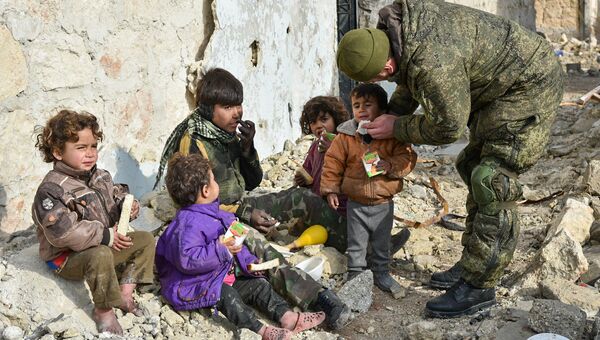 Военные инженеры сводного отряда Международного противоминного центра Вооруженных сил РФ, продолжающие работу по разминированию восточных районов сирийского города Алеппо, на одной из улиц Алеппо с сирийскими детьми