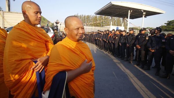 Буддийские монахи и полицейские перед храмом Ват Тхаммакай в Таиланде. Архивное фото