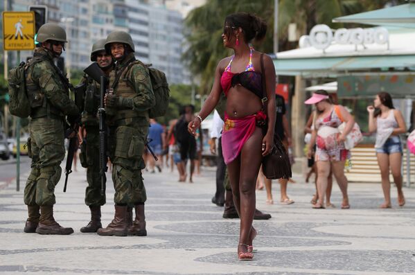 Бразильские военные смотрят на девушку на пляже Копакабана в Рио-де-Жанейро