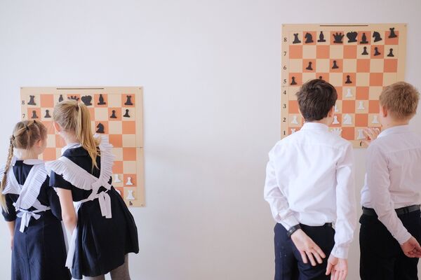 Ученики Лицея №48 играют в шахматы в коридоре во время внеклассных занятий школы в городе Краснодар
