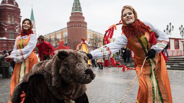 Участницы анимационной программы, одетые в праздничные костюмы, с актером в костюме медведя во время открытия фестиваля Московская масленица на Манежной площади
