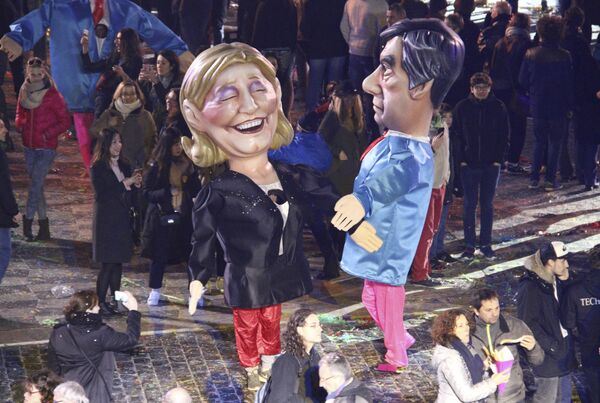 Артисты в костюмах, изображающих кандидатов на пост президента Франции Марин Ле Пен и Франсуа Фийона во время карнавала в Ницце