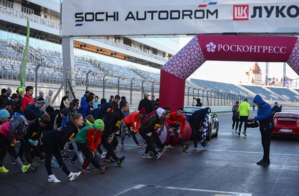 Участники легкоатлетического забега по трассе Гран-при России Формулы-1 в Сочи разминаются перед стартом