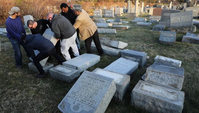 Местные жители устраняют послдствия акта вандализма на еврейском кладбище в Филадельфии. 26 февраля 2017