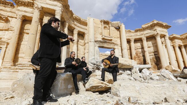 Сирийские музыканты играют на месте разрушенного римского амфитеатра в древнем городе Пальмира, Сирия