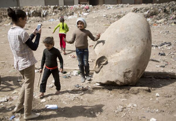 Ребенок фотографируется возле статуи древнеегипетского фараона Рамзеса Второго, обнаруженой археологами в районе Матария в Каире