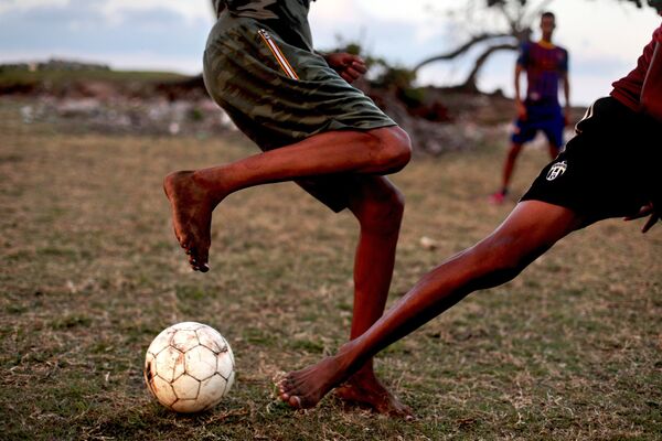 Кубинцы играют в футбол на бейсбольном стадионе в городе Баракоа