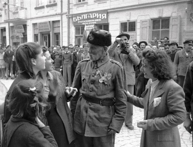 Ветеран турецкой войны беседует с девушками, в освобожденном войсками РККА от фашистов, болгарском городе