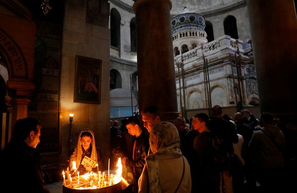 Прихожане зажигают свечи в отреставрированной Кувуклии в храме Гроба Господня в Иерусалиме
