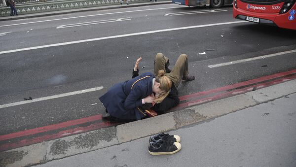 Девушка помогает раненному мужчине на Вестминстерском мосту в Лондоне