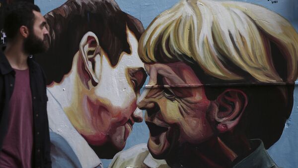 Граффити с изображением премьер-министра Греции Алексиса Ципраса и канцлера Германии Ангелы Меркель на улице в Афинах, Греция
