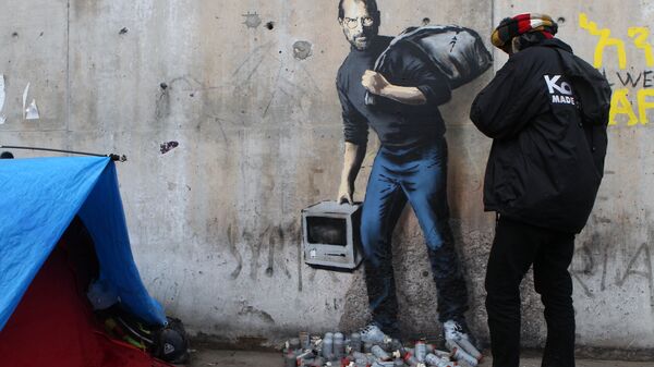 Граффити с изображением Стива Джобса художника Бэнкси на стене лагеря для беженцев в Кале, Франция. Архивное фото