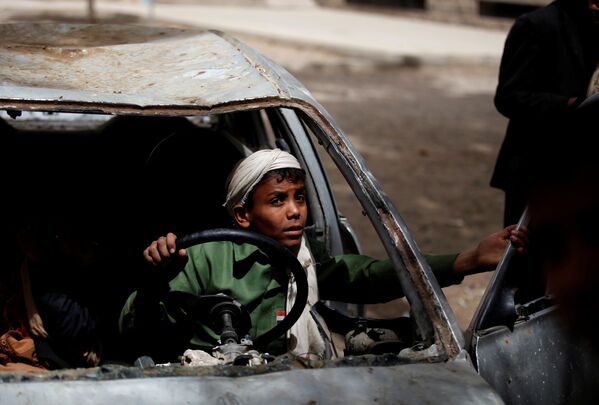 Мальчик играет в заброшенном автомобиле в Сане, Йемен