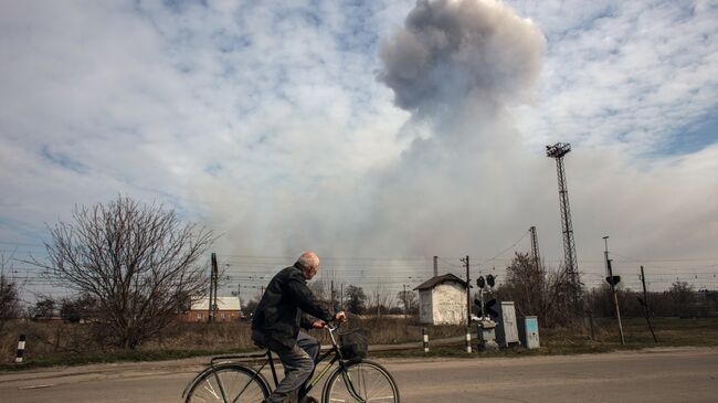 Мужчина на велосипеде на одной из улиц города Балаклея в Харьковской области во время пожара на военных складах боеприпасов