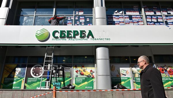 Рабочий очищает фасад центрального отделения дочернего предприятия Сбербанка России в Киеве от листовок. 28 марта 2017
