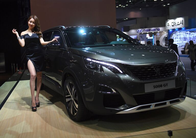 Модель позирует с автомобилем Peugeot 5008GT в Сеульском автосалоне