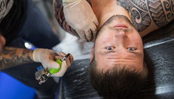 Тату-мастер наносит новую татуировку на тело мужчины