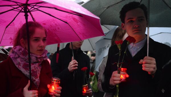 Молодые люди с цветами в память о погибших в результате взрыва в метро Санкт-Петербурга у стеллы города Ленинград на Аллее Городов-героев в Москве