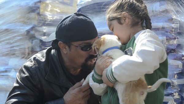 Американский актер Стивен Сигал рассматривает семимесячного щенка, взятого в одном из приютов Бухареста