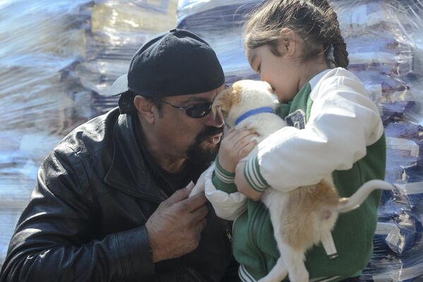 Американский актер Стивен Сигал рассматривает семимесячного щенка, взятого в одном из приютов Бухареста