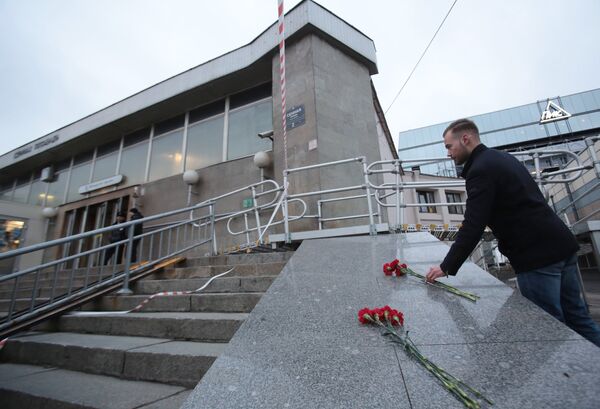 Мужчина возлагает цветы у входа в вестибюль станции метро Сенная площадь в Санкт-Петербурге