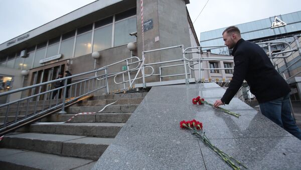 Мужчина возлагает цветы у входа в вестибюль станции метро Сенная площадь в Санкт-Петербурге