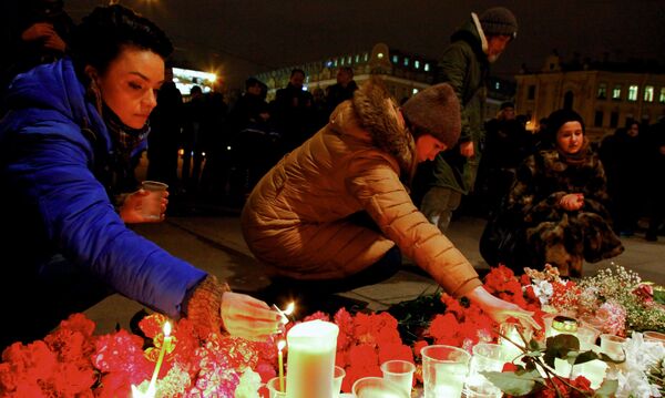 Горожане зажигают свечи у входа в вестибюль станции метро Спасская в память о погибших в результате взрыва в метро Санкт-Петербурга