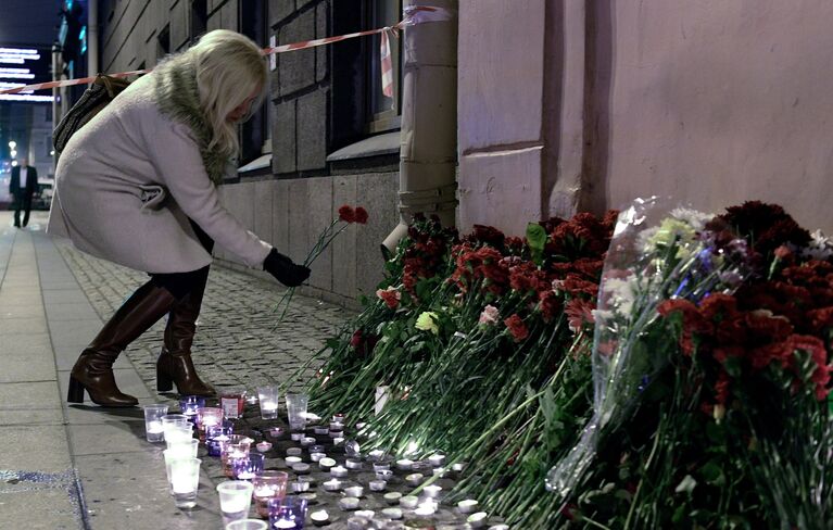 Женщина возлагает цветы рядом со станцией метро Технологический институт в память о погибших в результате взрыва в метро Санкт-Петербурга