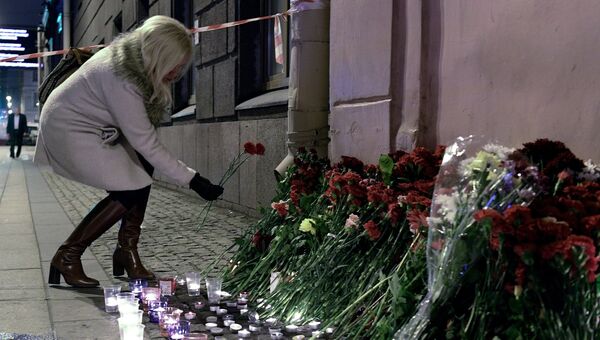 Женщина возлагает цветы рядом со станцией метро Технологический институт в память о погибших в результате взрыва в метро Санкт-Петербурга