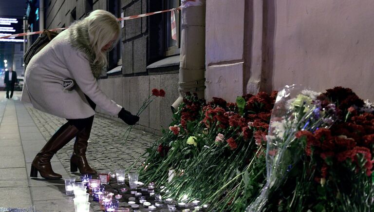 Женщина возлагает цветы рядом со станцией метро Технологический институт в память о погибших в результате взрыва в метро Санкт-Петербурга