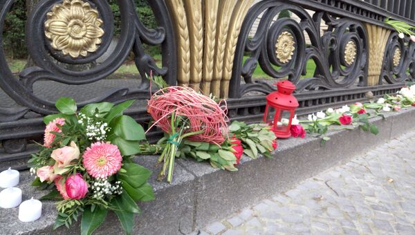 Жители Берлина несут цветы к российскому посольству в центре немецкой столицы