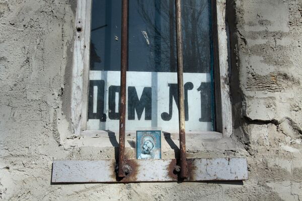 Икона в окне дома на улице Привокзальной в прифронтовом поселке Донецк-Северный в Донецкой области