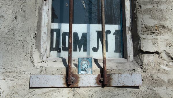 Икона в окне дома на улице Привокзальной в прифронтовом поселке Донецк-Северный в Донецкой области