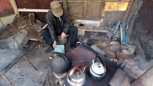 Местный житель следит на улице за печкой, на который жители многоквартирного дома греют чайники