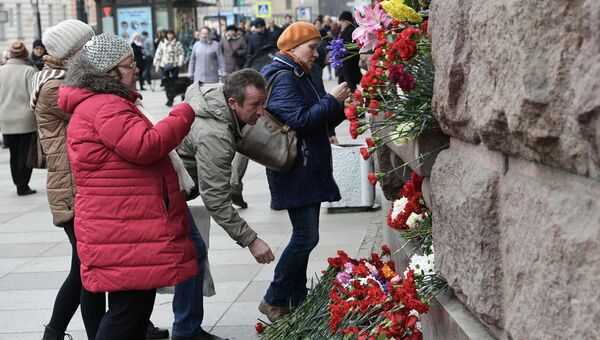 Люди возлагают цветы у станции метро Технологический институт, где накануне произошел взрыв