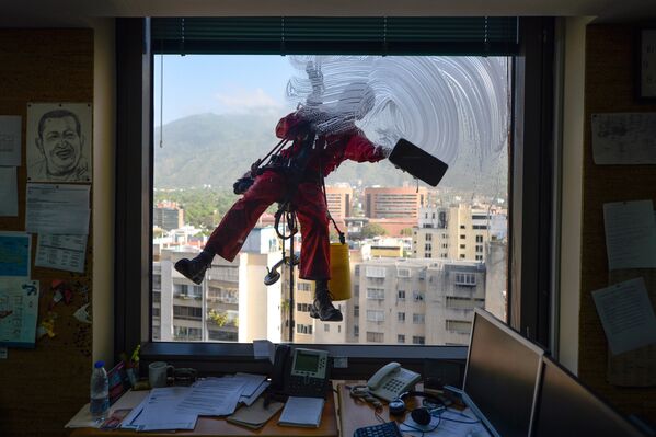 Работник моет окно офисного здания в Каракасе, Венесуэла