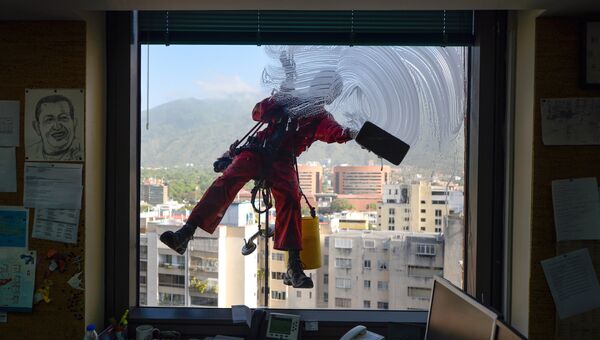 Работник моет окно офисного здания в Каракасе, Венесуэла