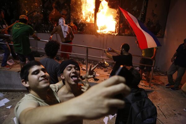 Мужчины фотографируются во время протестов против принятия поправки в конституцию в Асунсьоне, Парагвай