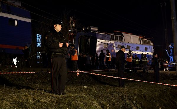 Сотрудники правоохранительных органов стоят в оцеплении на месте столкновения пассажирского поезда и электрички в районе улицы Герасима Курина в Москве