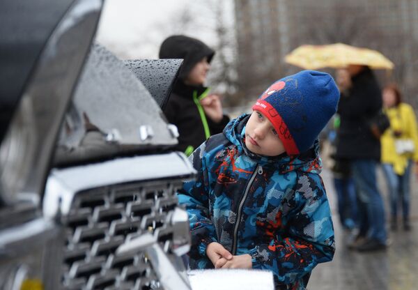 Мальчик рассматривает автомобиль ГАЗ 13 Чайка перед стартом автопробега 108 минут в Москве, приуроченного к 56-й годовщине полета человека в космос