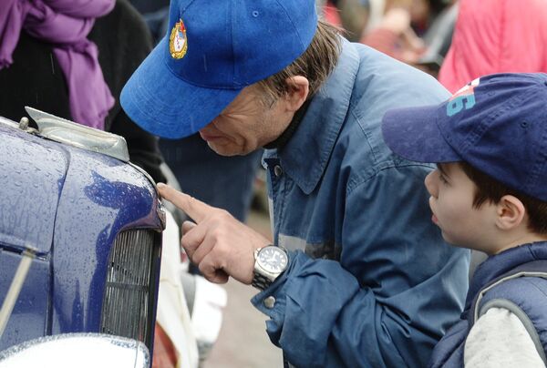 Мужчина с ребенком у автомобиля ГАЗ М1 перед стартом автопробега 108 минут в Москве, приуроченного к 56-й годовщине полета человека в космос