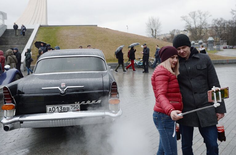 Жители Москвы фотографируются у автомобиля ГАЗ 13 Чайка перед стартом автопробега 108 минут в Москве, приуроченного к 56-й годовщине полета человека в космос