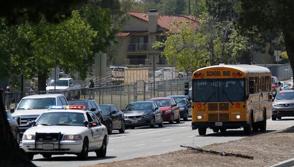 Полиция сопровождает школьный автобус во время эвакуации после стрельбы в начальной школе в Сан-Бернардино, Калифорния