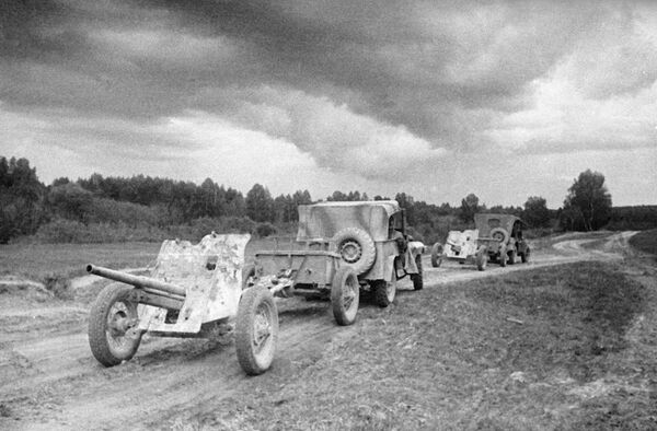 Машины ГАЗ-67 тянут по дороге артиллерийские орудия